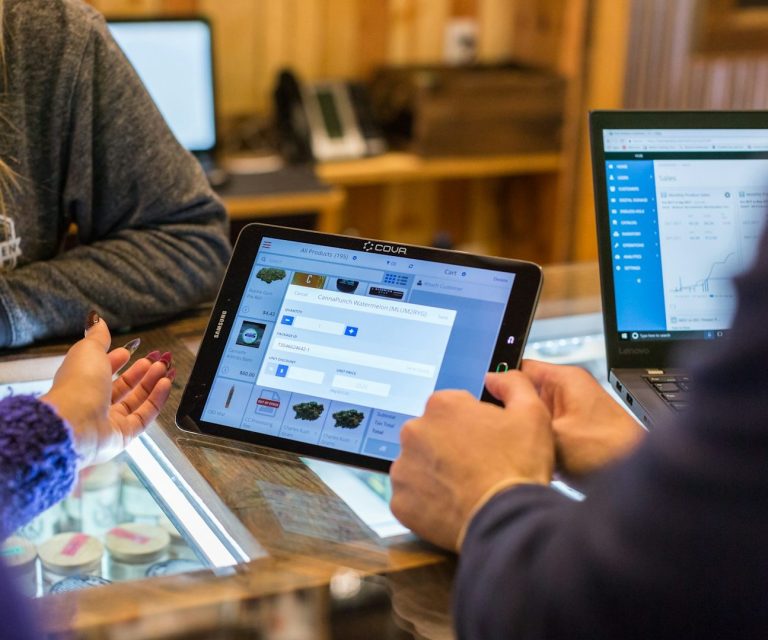 Personen verwenden Tablets und Laptops zur Datenbearbeitung in einem Holzinterieur.
